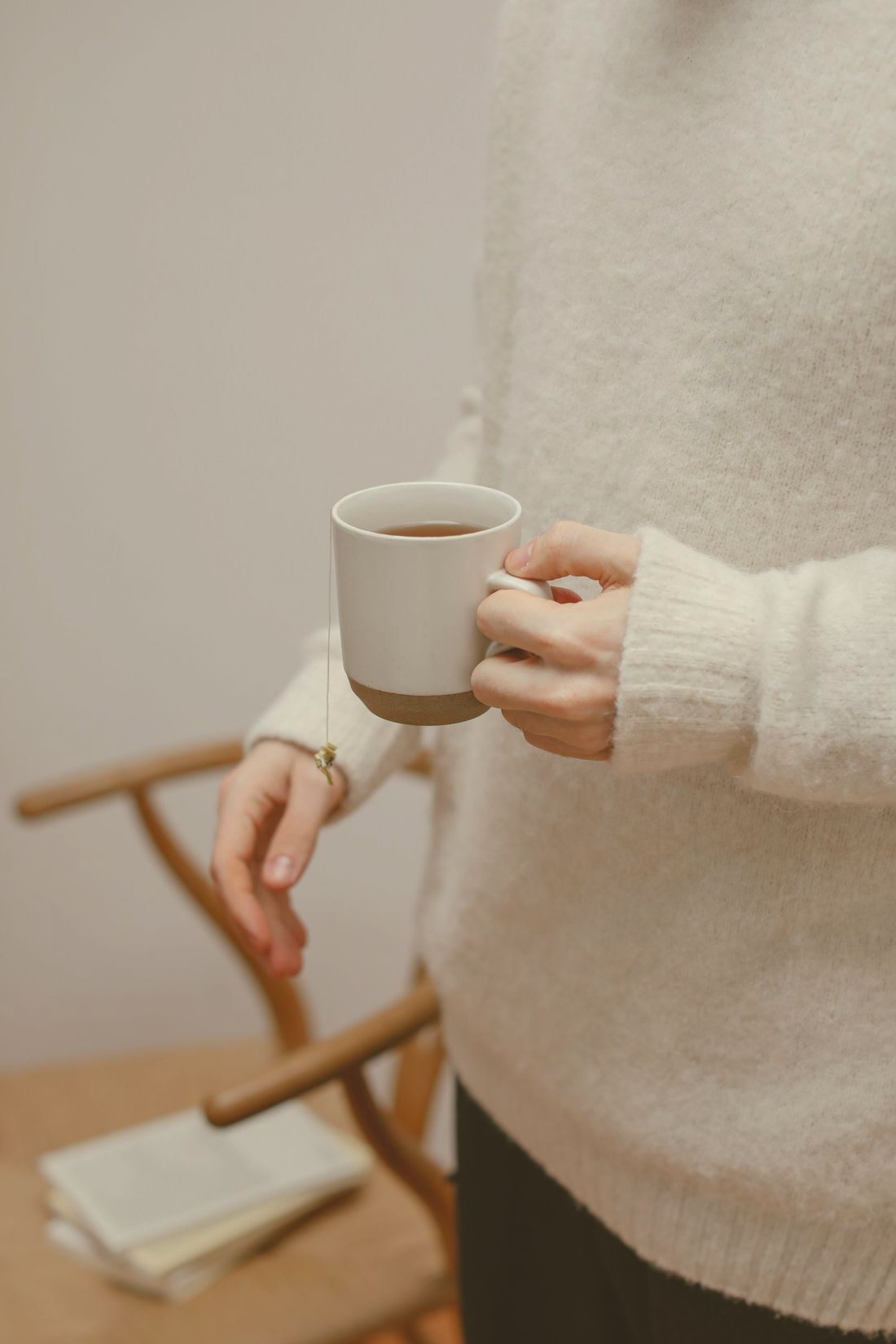 Hands wrapped around a warm mug of tea beside a sunny window