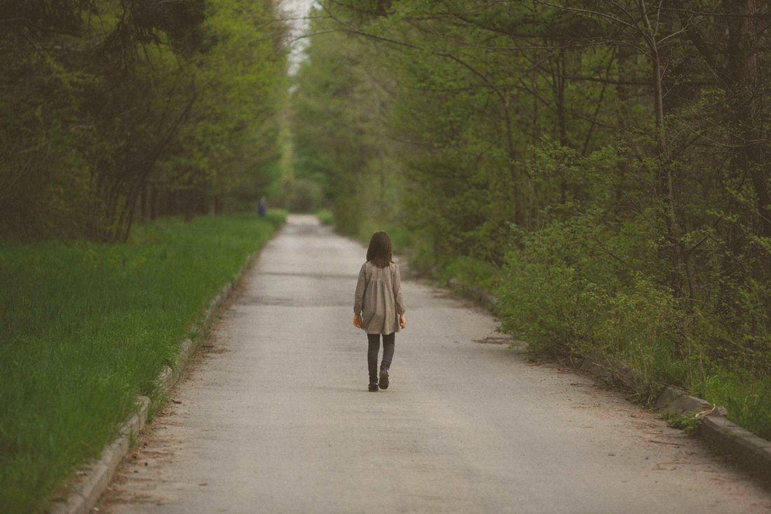 Person walking a quiet tree-lined road, a calm image for therapy for Burlington residents at our Oakville offices